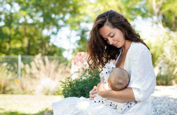 woman nursing baby girl outdoors in backyard MQT78MC copy